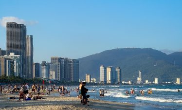 Beach city skyline with modern buildings and mountain backdrop in Vietnam.