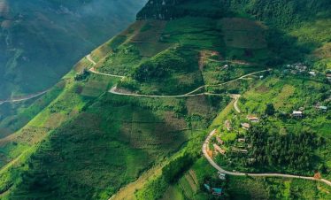 Ha Giang scenic mountain pass with winding roads and lush greenery.