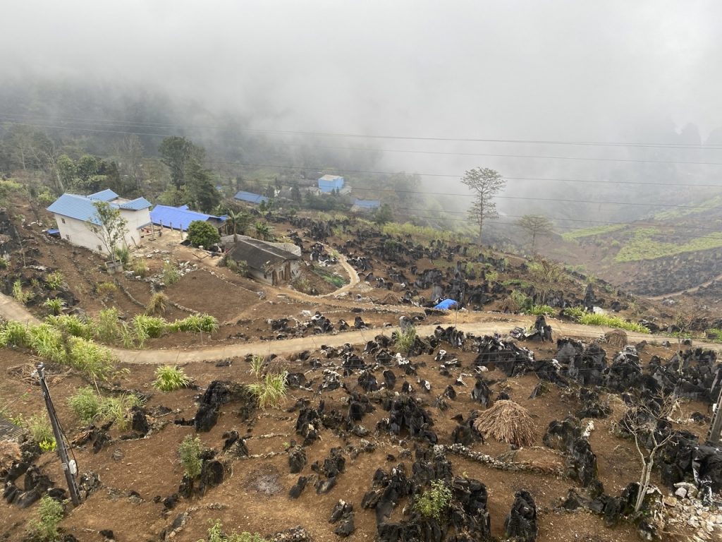 Scenic view of lush mountains and traditional villages in Ha Giang with misty atmosphere.