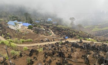 Scenic view of lush mountains and traditional villages in Ha Giang with misty atmosphere.