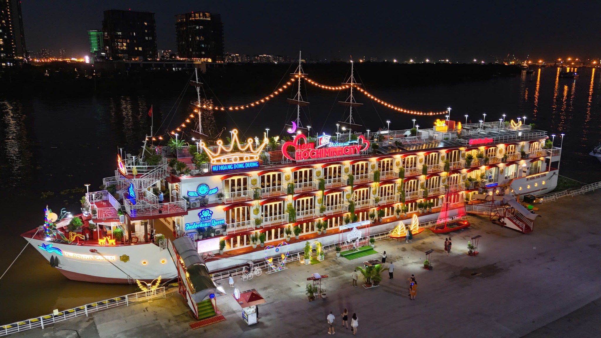 Luxury cruise boat illuminated at night on Halong Bay, showcasing vibrant lights and elegant design.