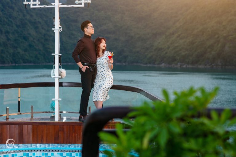 Scenic Lan Ha Bay cruise balcony with couple soaking in breathtaking views, embodying luxury and tra.