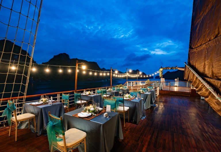 Elegant dinner setup on a Halong Bay cruise with stunning sunset views.