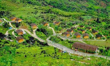 Vivid view of lush green hills and winding roads in Ha Giang, showcasing traditional houses and vibr.