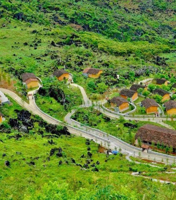 Vivid view of lush green hills and winding roads in Ha Giang, showcasing traditional houses and vibr.