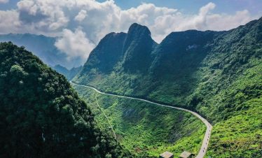 Breathtaking view of Ha Giang mountains with winding road and lush greenery, perfect for adventure t.