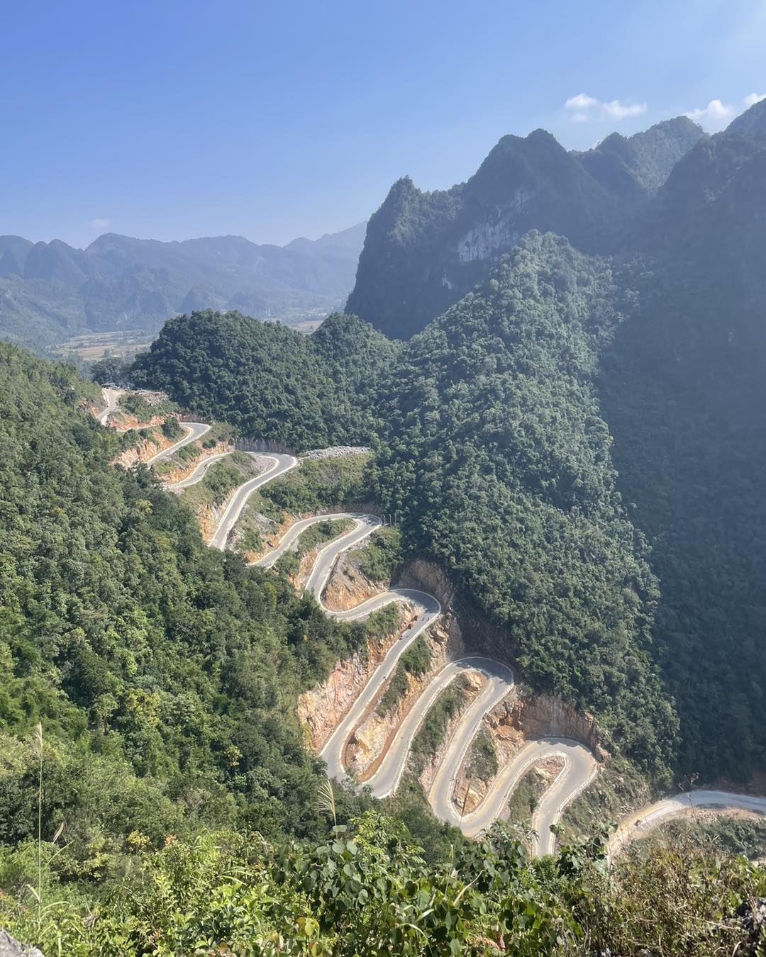 Winding mountain road through lush green peaks, perfect for trekking and adventure travel in Vietnam.