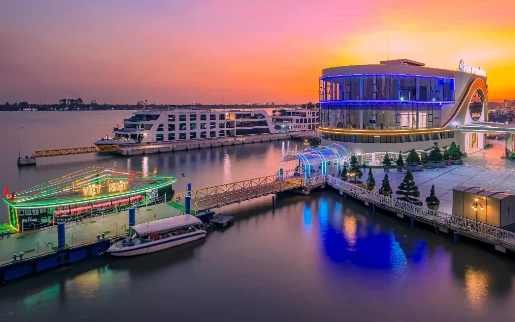 A modern luxury cruise docked at sunset in Halong Bay, showcasing stunning waters and vibrant sky.