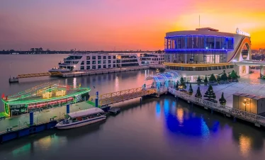 A modern luxury cruise docked at sunset in Halong Bay, showcasing stunning waters and vibrant sky.