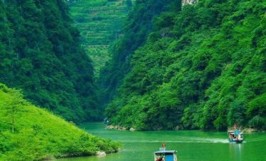 Scenic river scene with boats navigating lush green cliffs in Vietnam's tranquil landscape.