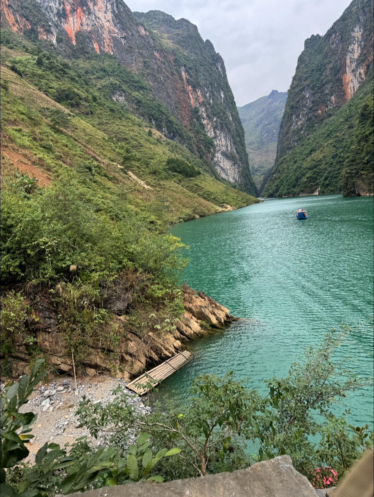 Stunning view of Ha Giang Lake surrounded by towering green cliffs, perfect for trekking and nature.