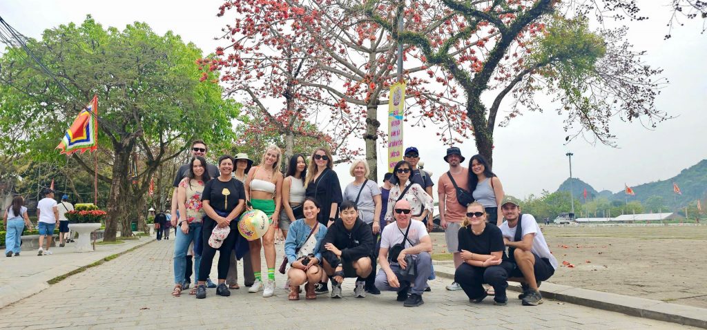 Vibrant group photo in Sapa with lush mountain scenery and blooming trees, capturing the essence of.