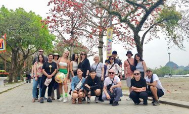 Vibrant group photo in Sapa with lush mountain scenery and blooming trees, capturing the essence of.