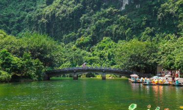Scenic view of a lush green river in Sapa with trekking activity and vibrant natural surroundings.