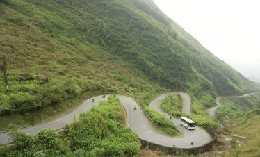 Scenic winding road through lush green mountains in Ha Giang, perfect for adventure and exploration.
