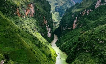Stunning view of lush green valleys and winding river in Vietnam, perfect for trekking and nature ex.