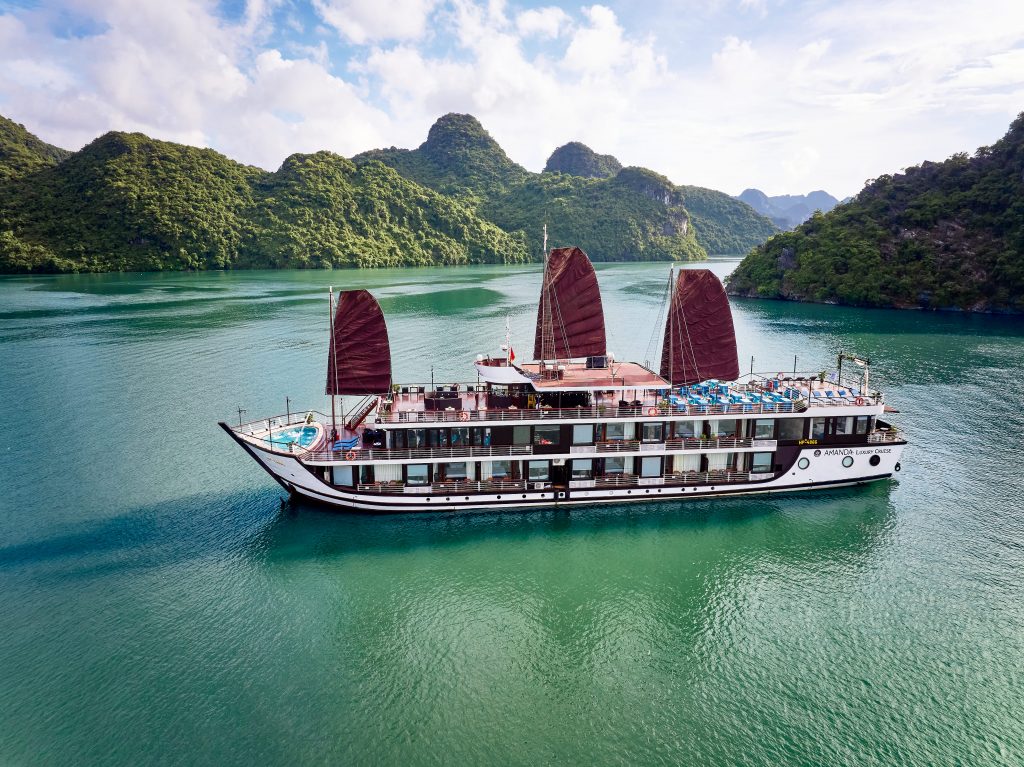 A stunning Halong Bay cruise featuring traditional sailboats amidst emerald waters and towering lime.