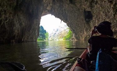 Kayaking inside a stunning cave in Halong Bay, surrounded by lush greenery and clear waters, perfect.