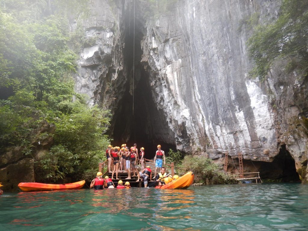 Kayakers exploring the stunning limestone caves in Halong Bay, surrounded by emerald waters and lush.