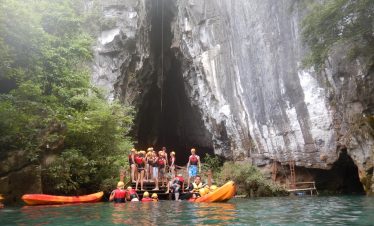 Kayakers exploring the stunning limestone caves in Halong Bay, surrounded by emerald waters and lush.