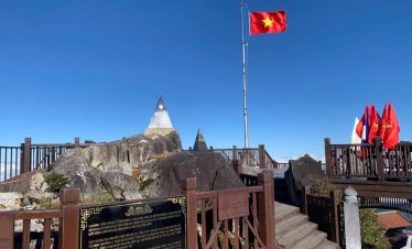 Stunning view of Sapa mountain with flag and scenic landscape, perfect for trekking and cultural exp.