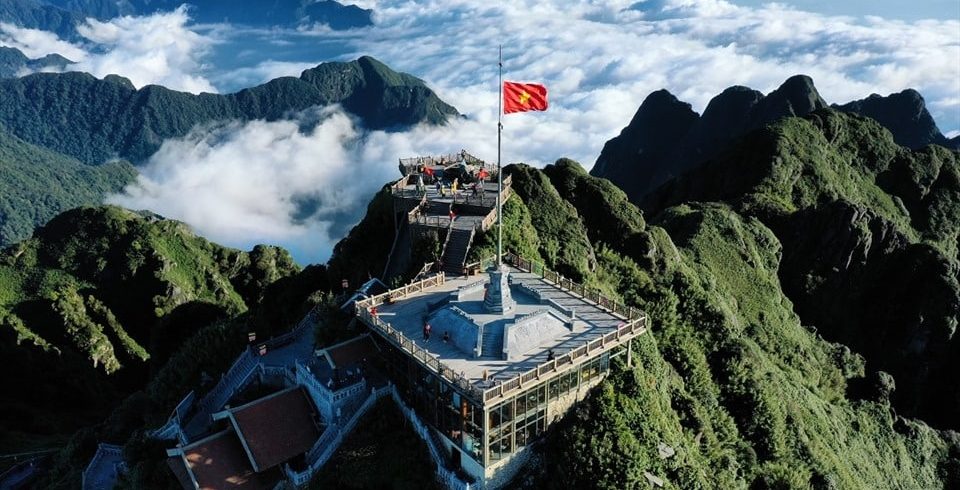 Spectacular view from Fansipan peak showcasing lush green mountains and clouds, perfect for trekking.