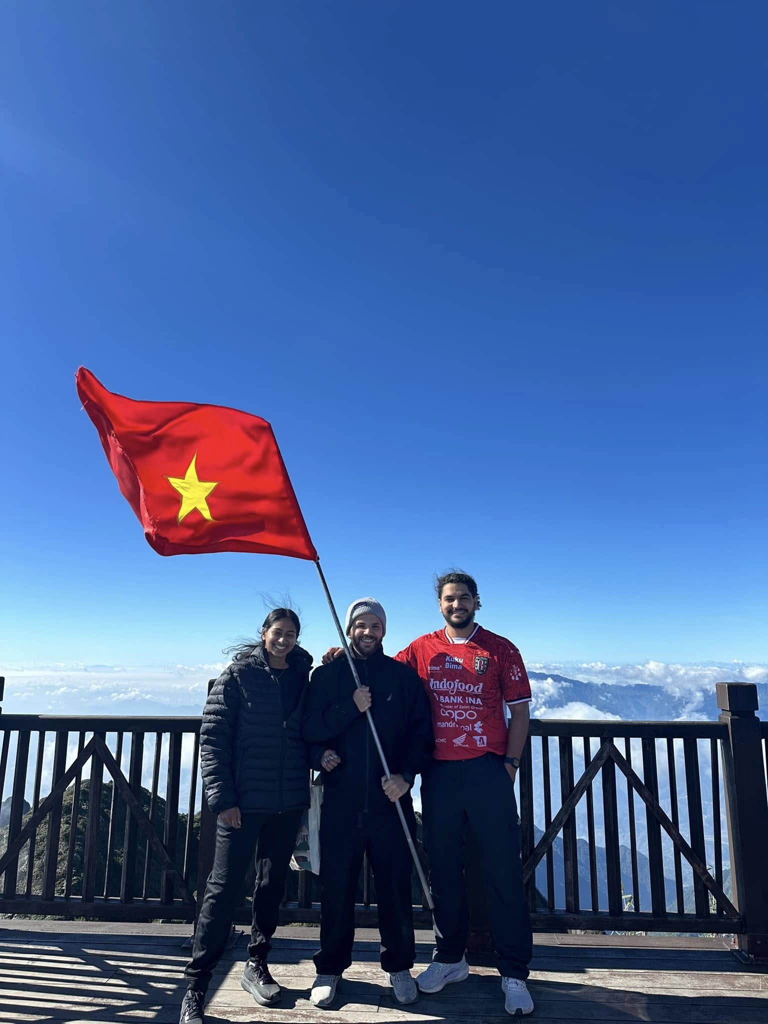 People enjoying trekking on Mount Fansipan with clear blue sky in the background.