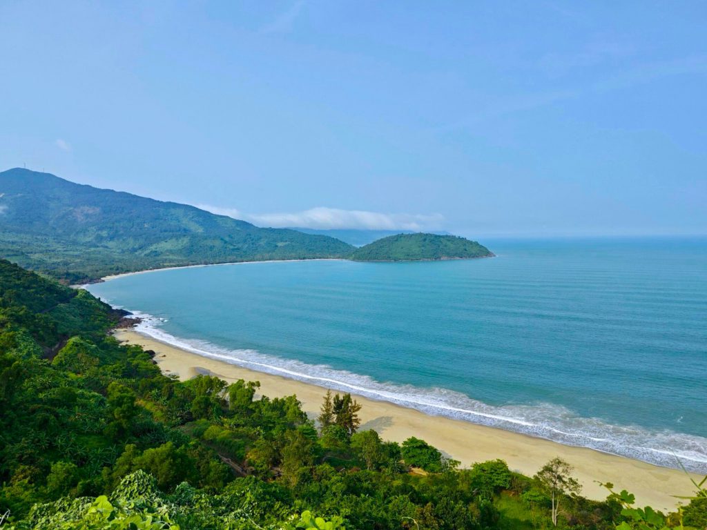 Stunning coastal scenery along Hue to Hoi An route, showcasing lush greenery and tranquil beach view.
