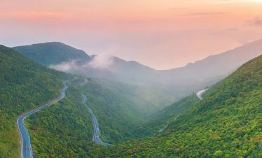 A winding mountain road through lush green hills in Vietnam at dawn, evoking adventure and tranquili.
