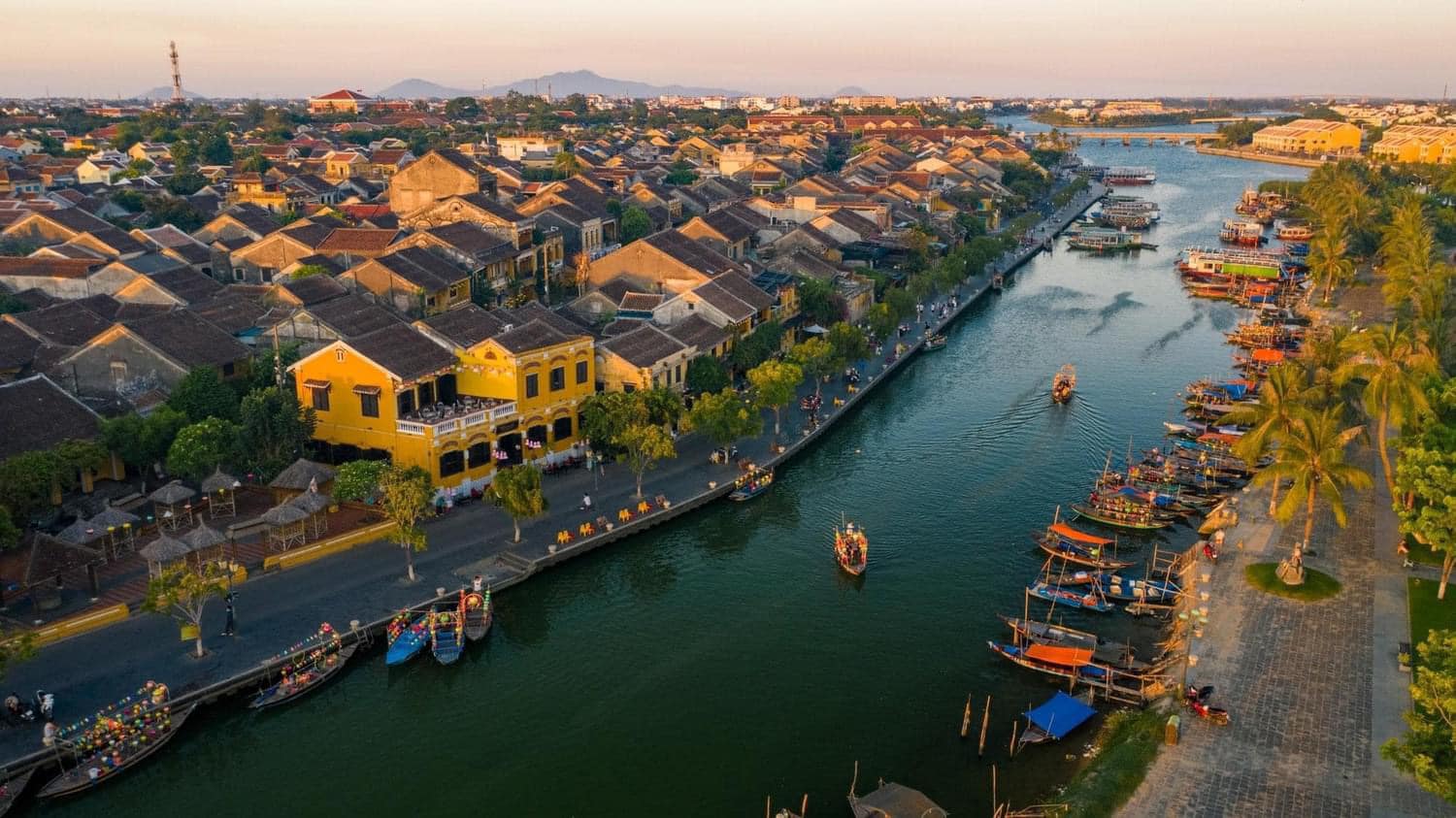 Scenic river view of a traditional Vietnamese town with boats and colorful buildings along the water.