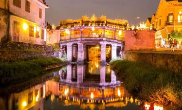 Night view of ancient bridge in Hue with reflections on the water, vibrant city lights, and historic.