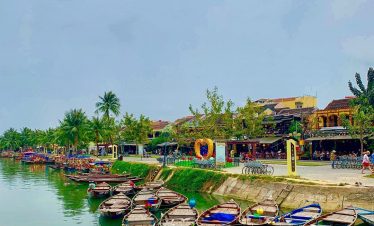 Scenic riverside view in Hue with boats docked along the tranquil waterway, showcasing Vietnam's ric.