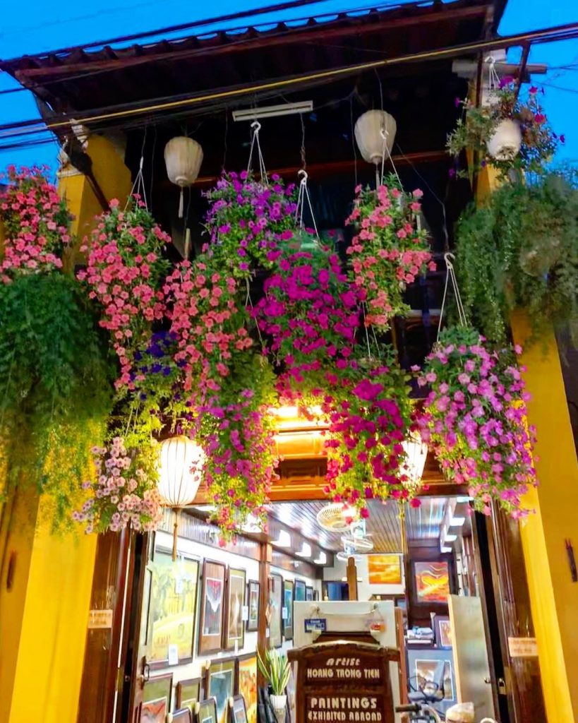 Vibrant hanging flowers and lanterns create a lively atmosphere in Hanoi's artistic district.
