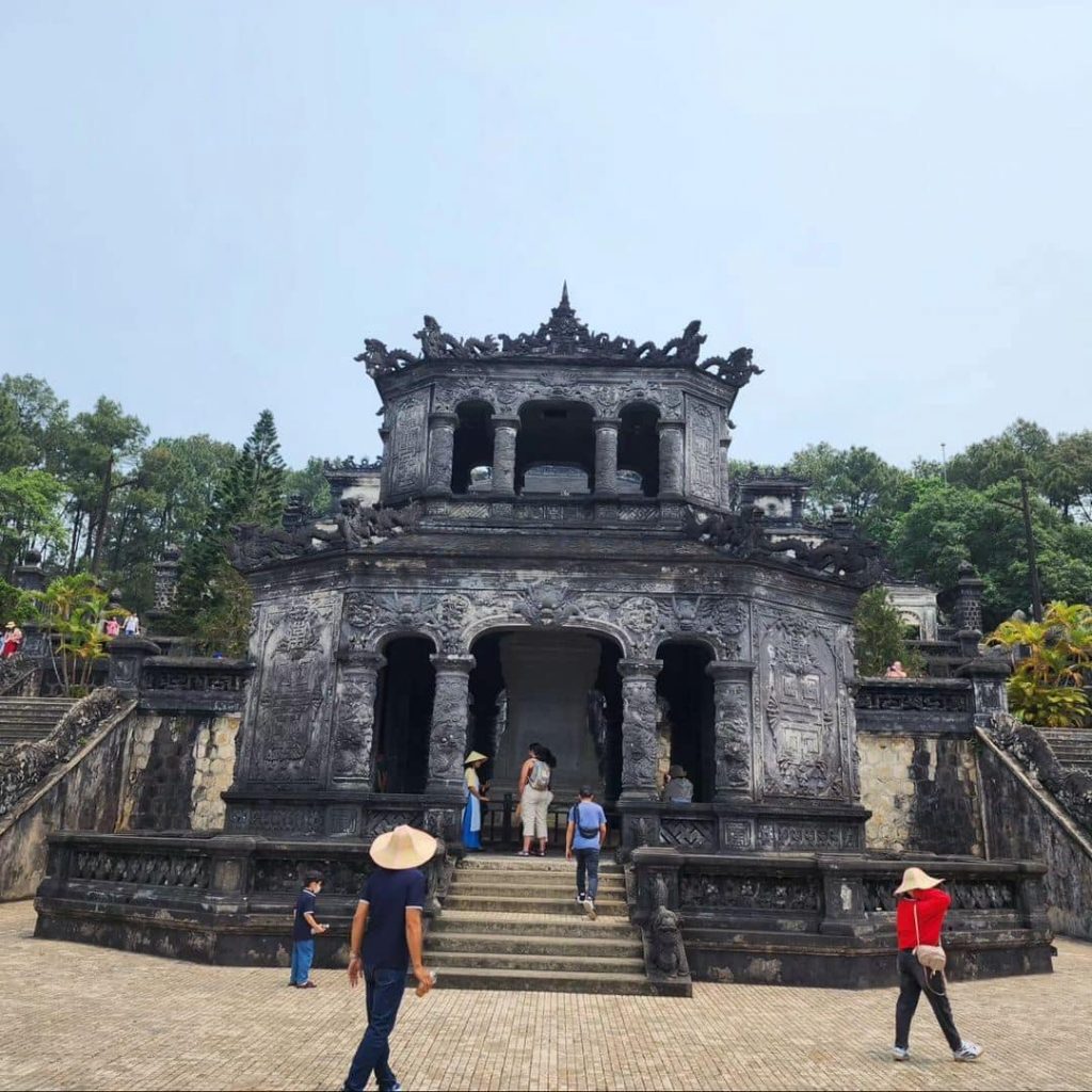 Ancient Hue temple with visitors exploring historic architecture and lush surroundings.