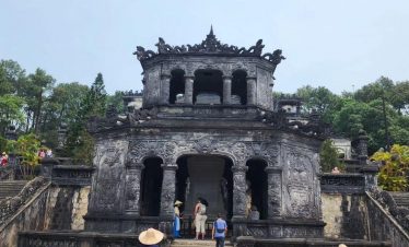 Ancient Hue temple with visitors exploring historic architecture and lush surroundings.