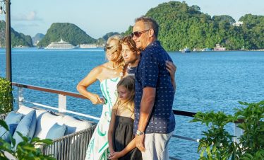 Family enjoying a scenic Halong Bay cruise balcony with stunning views and serene waters.