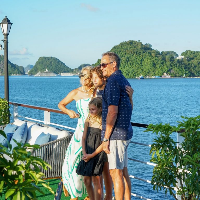 Family enjoying a scenic Halong Bay cruise balcony with stunning views and serene waters.