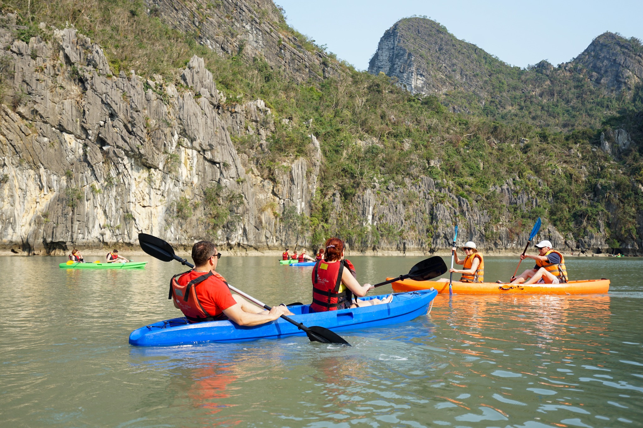Kayakers exploring Lan Ha Bay's tranquil waters with stunning limestone cliffs.