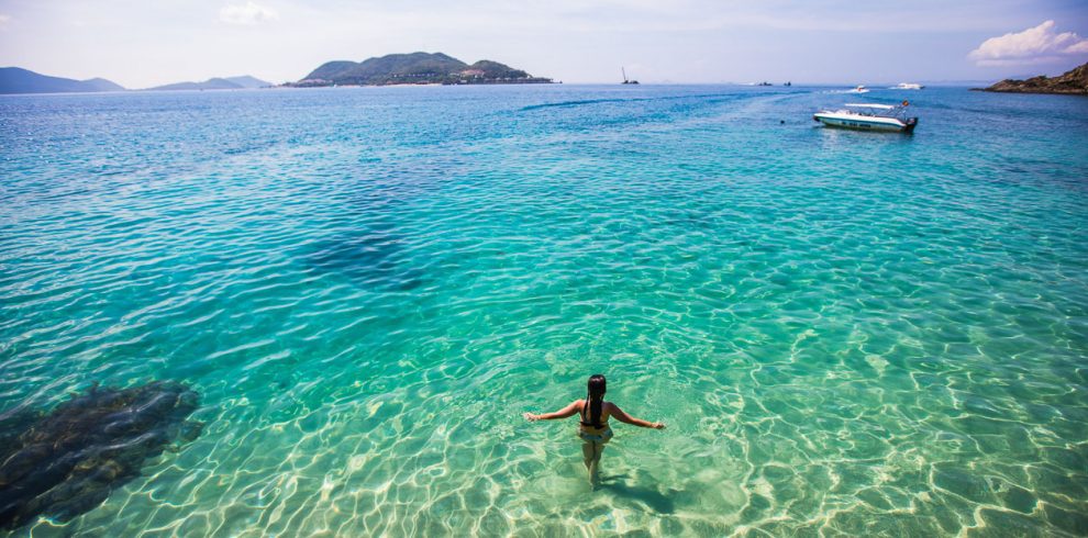 Stunning woman relaxing in clear turquoise waters of Halong Bay, Vietnam, during a luxurious cruise.