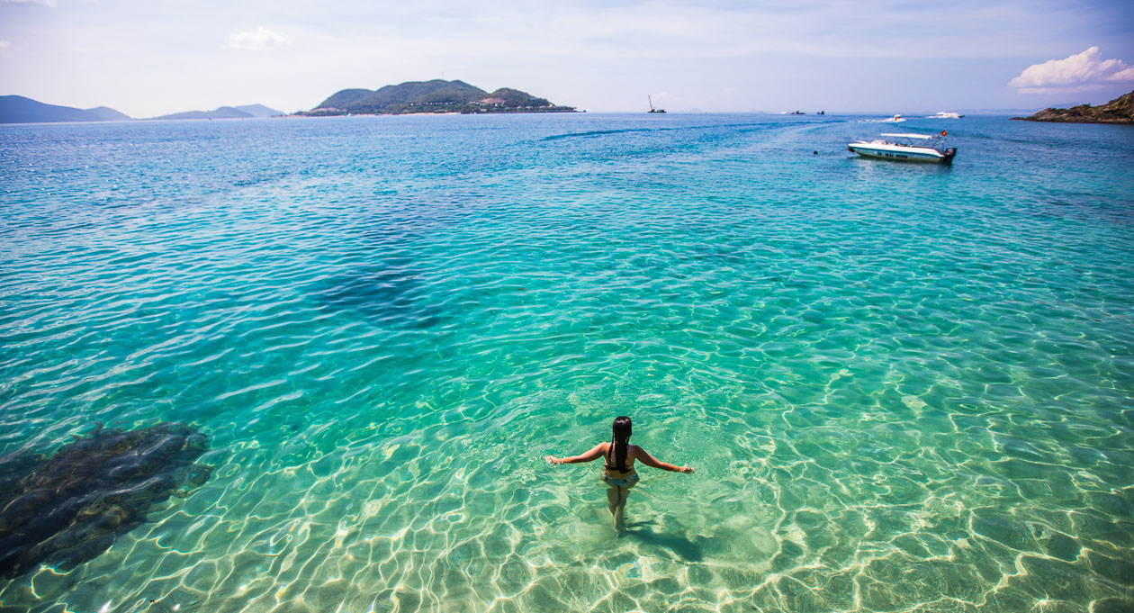 Stunning woman relaxing in clear turquoise waters of Halong Bay, Vietnam, during a luxurious cruise.