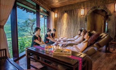 Relaxing spa treatment with guests enjoying massage in a cozy wooden room overlooking lush mountains.