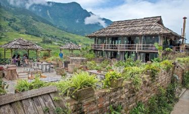 A peaceful scene of a rustic wooden house amidst verdant mountains, perfect for exploring Vietnam’s.
