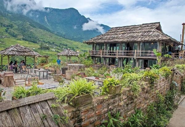A peaceful scene of a rustic wooden house amidst verdant mountains, perfect for exploring Vietnam’s.