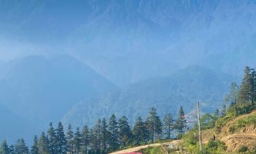 Scenic mountain train crossing lush green hills with towering peaks in Vietnam.