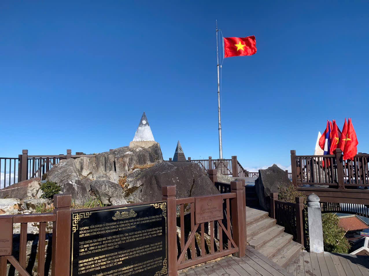 Vietnam flag flying high on historic site with scenic mountain backdrop, symbolizing national pride.