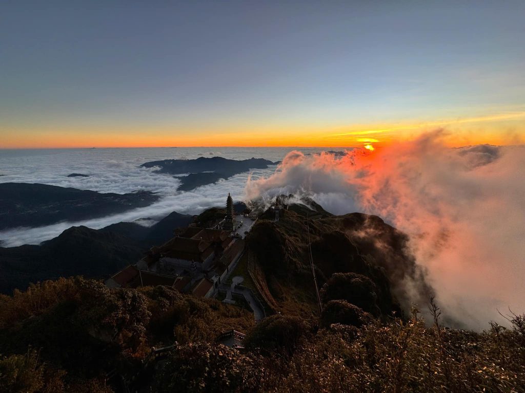 Majestic sunset view from Fansipan Mountain with clouds and rugged terrain, perfect for trekking and.