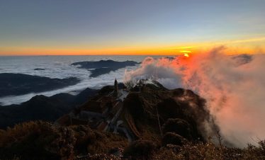 Majestic sunset view from Fansipan Mountain with clouds and rugged terrain, perfect for trekking and.