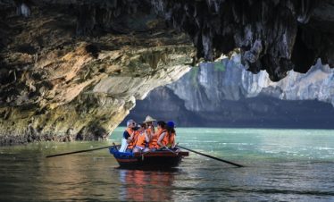 Kayakers exploring Halong Bay's serene waters beneath dramatic limestone cliffs, capturing the essen.