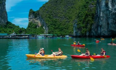 Kayakers exploring the emerald waters of Halong Bay surrounded by towering limestone cliffs.