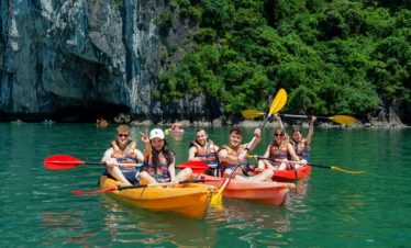Vivid scene of travelers kayaking on emerald waters surrounded by towering limestone cliffs in Halon.